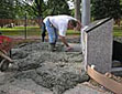 A worker from Buren Concrete Forming starts to trowel the freshly poured concrete of the sidewalk in front of the Memorial.